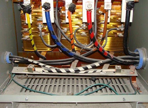 Photo. 2. Note in the photo how the 3/0 AWG bare copper grounding electrode conductor originates from the neutral point XO and pierces through the mesh in the bottom of the transformer enclosure. Because the grounding electrode conductor is not solidly bonded to the transformer enclosure, this is no compliant system bonding jumper for this separately derived system.