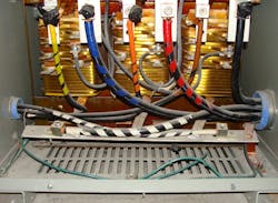 Photo. 2. Note in the photo how the 3/0 AWG bare copper grounding electrode conductor originates from the neutral point XO and pierces through the mesh in the bottom of the transformer enclosure. Because the grounding electrode conductor is not solidly bonded to the transformer enclosure, this is no compliant system bonding jumper for this separately derived system. Photo. 2. Note in the photo how the 3/0 AWG bare copper grounding electrode conductor originates from the neutral point XO and pierces through the mesh in the bottom of the transformer enclosure. Because the grounding electrode conductor is not solidly bonded to the transformer enclosure, this is no compliant system bonding jumper for this separately derived system.