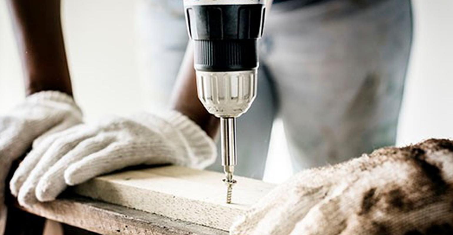 worker drilling screw into board