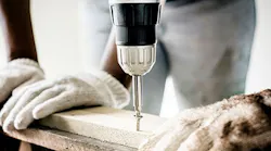 worker drilling screw into board