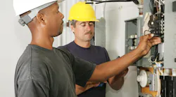 Electricians with meters examine circuit breaker load center
