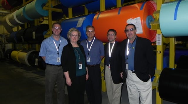 Jeremiah Blair, 3M global marketing manager; Brad Blietz, 3M global business manager; Marty Riesberg, NJATC director of curriculum development; Steve Anderson, NJATC director of line construction curriculum development and training; and Mary Carlson, manufacturing director for 3M&apos;s Electrical Markets Division, stand in the &apos;jumbo&apos; store room at the 3M Hutchinson plant. NJATC toured the plant where 3M makes Scotch Super 33 vinyl electrical tape to celebrate the new strategic collaboration between the organizations.