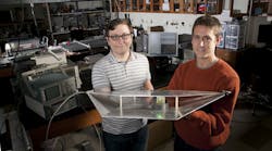 Duke engineering students Alexander Katko (left) and Allen Hawkes show a waveguide containing a single power-harvesting metamaterial cell, which provides enough energy to power the attached green LED.