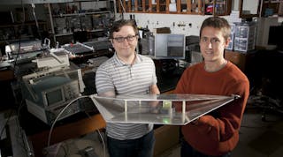 Duke engineering students Alexander Katko (left) and Allen Hawkes show a waveguide containing a single power-harvesting metamaterial cell, which provides enough energy to power the attached green LED.