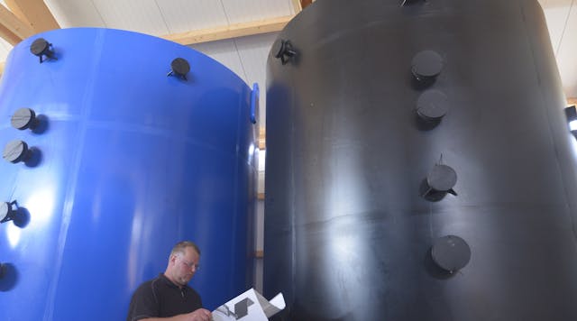 The Bosch associate Ralf Gaudig in front of two large tanks that are part of the Braderup vanadium redox flow battery