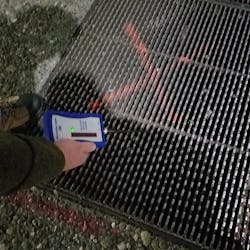 Photo 2. Metal grate being screened using handheld voltage detector. Photo 2. Metal grate being screened using handheld voltage detector.