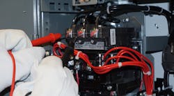 Photo 1. It is possible to drag an electrical arc from Phase B to Phase C (center to right terminals) when measuring voltage. Notice that the worker is pulling the black test lead toward him or herself before placing it on Phase C. Simply sliding the black test lead from the center to the right-hand terminal could establish a phase-to-phase arcing fault through the airspace between the terminals. Photo 1. It is possible to drag an electrical arc from Phase B to Phase C (center to right terminals) when measuring voltage. Notice that the worker is pulling the black test lead toward him or herself before placing it on Phase C. Simply sliding the black test lead from the center to the right-hand terminal could establish a phase-to-phase arcing fault through the airspace between the terminals.