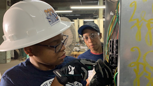Asia Wilkerson (left), a TAIA School student, and Dana Pinkney, licensed master electrician (right), install a 20A 3-phase branch circuit for a commercial edge bander in a cabinet manufacturing facility in Philadelphia.
