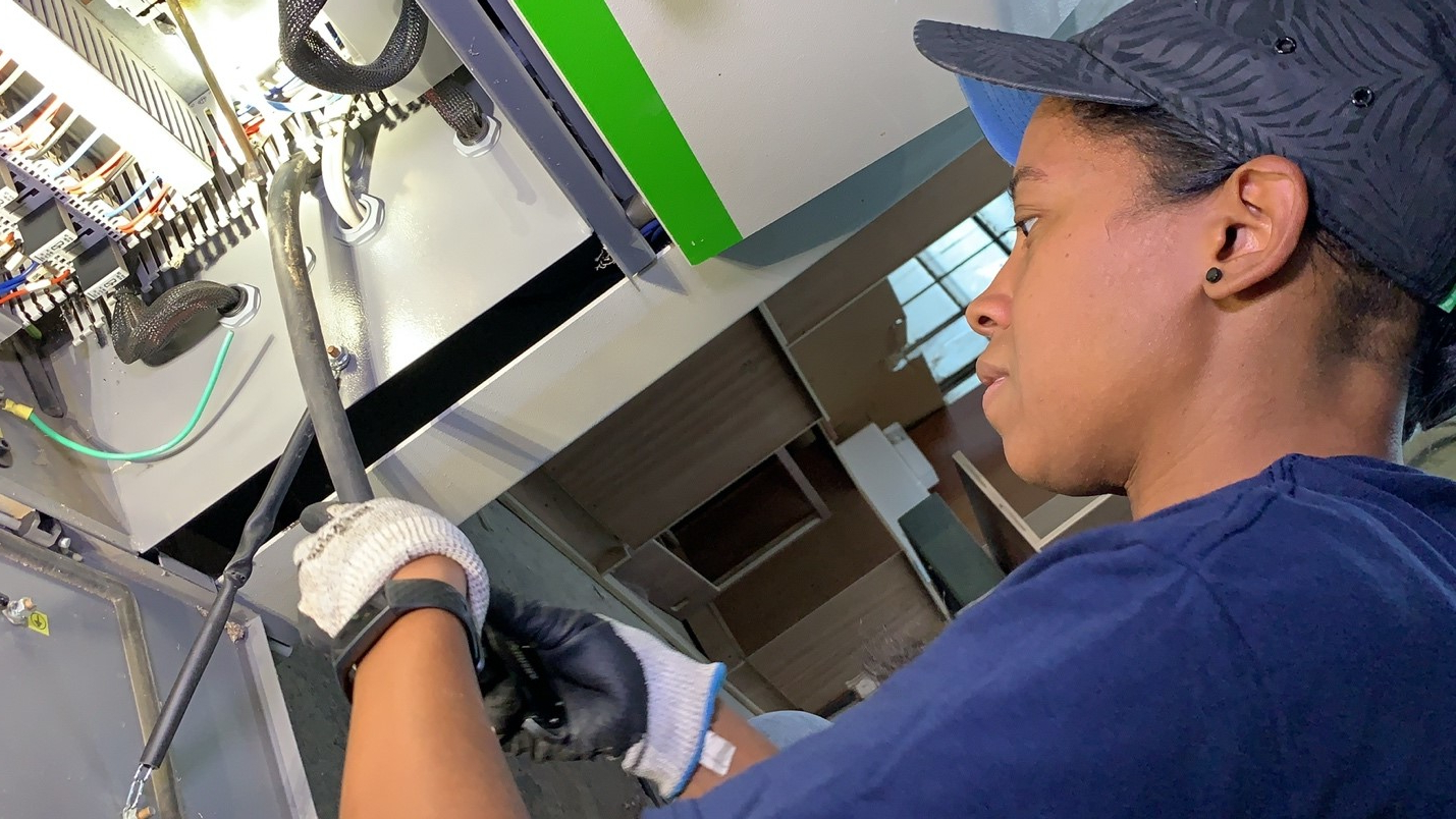 Dana Pinkney, a licensed master electrician, installs a power supply cord to a three-phase commercial edge bander in a commercial cabinetry shop in Philadelphia.
