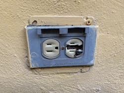 Damaged electrical outlet and receptacle on an outdoor wall