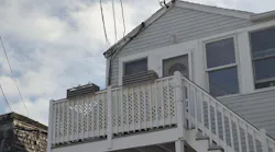 Service conductors attached to the roof edge of gray two story house
