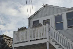 Service conductors attached to the roof edge of gray two story house