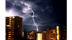 Lightning bolt in nighttime sky with large buildings in foreground Lightning bolt in nighttime sky with large buildings in foreground