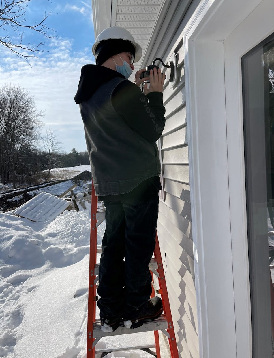 Senor installs outdoor lighting on a cold winter day, one of the regular challenges faced by Catalano and the students while working in Eastern New York.
