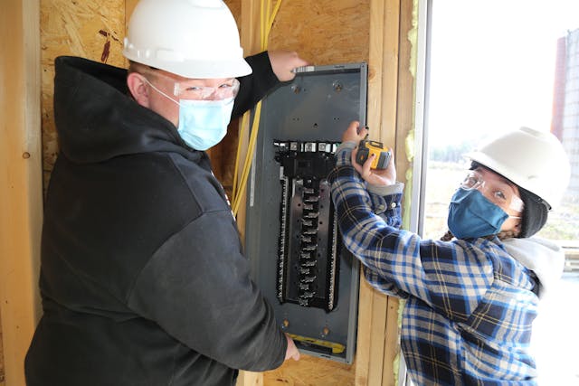 Jonathan Toth and Kaitlyn Lennon work together to hang an electrical panel.
