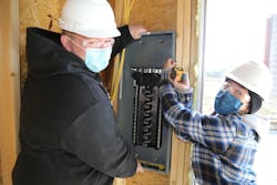 Jonathan Toth and Kaitlyn Lennon work together to hang an electrical panel. Jonathan Toth and Kaitlyn Lennon work together to hang an electrical panel.