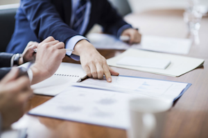 Hand pointing to paperwork on a desk