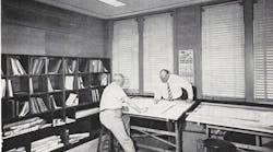 Two Men At A Drafting Table In A Group Office