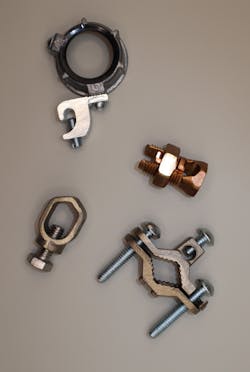 Photo 3a. Pressure connectors listed as grounding and bonding are evaluated under UL 487 for grounding and bonding applications only and may not be used for power conductor connections. From top clockwise: Grounding bushing, split-bolt (also evaluated for other applications), ground clamp, cable-to-ground rod clamp (acorn clamp). Photo 3a. Pressure connectors listed as grounding and bonding are evaluated under UL 487 for grounding and bonding applications only and may not be used for power conductor connections. From top clockwise: Grounding bushing, split-bolt (also evaluated for other applications), ground clamp, cable-to-ground rod clamp (acorn clamp).