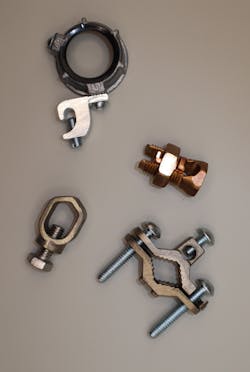 Photo 3a. Pressure connectors listed as grounding and bonding are evaluated under UL 487 for grounding and bonding applications only and may not be used for power conductor connections. From top clockwise: Grounding bushing, split-bolt (also evaluated for other applications), ground clamp, cable-to-ground rod clamp (acorn clamp). Photo 3a. Pressure connectors listed as grounding and bonding are evaluated under UL 487 for grounding and bonding applications only and may not be used for power conductor connections. From top clockwise: Grounding bushing, split-bolt (also evaluated for other applications), ground clamp, cable-to-ground rod clamp (acorn clamp).
