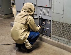 Photo 2. Installing a remote racking motor on a 480V low-voltage power circuit breaker is a common task that exposes workers to potentially a severe arc flash hazard. The domino effect could come into play: The work area is hot and uncomfortable; the hood makes it hard to breathe, and fog may accumulate on the face shield, making it hard to see. The breaker location on the bottom row is not an easy place to work. Frustration getting the motor to latch on the breaker could abruptly move the breaker enough to allow unmaintained equipment to fail and produce an arc flash. The worker does not have his arc-rated shirt tucked in which should have been addressed in the job briefing. What other pressures, concerns, or physical impairments may be affecting this worker?
