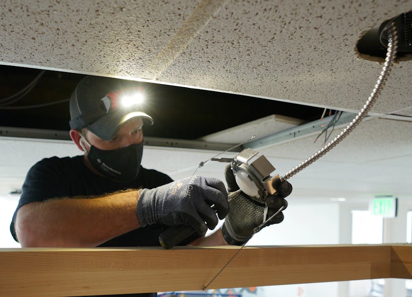 An electrician installs a networked sensor (with occupancy and light detection).