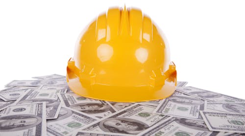 construction helmet on pile of hundred dollar bills
