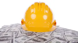 construction helmet on pile of hundred dollar bills