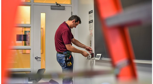 Photo 3. Maintenance worker adjusts a wall control device.