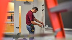Photo 3. Maintenance worker adjusts a wall control device. Photo 3. Maintenance worker adjusts a wall control device.