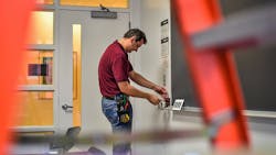 Photo 3. Maintenance worker adjusts a wall control device. Photo 3. Maintenance worker adjusts a wall control device.