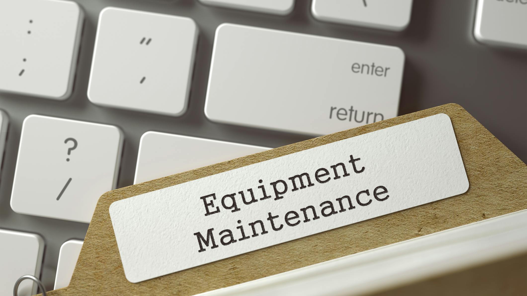 A folder with a tab that says 'Equipment Maintenance' rests on top of a keyboard.