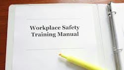 A white binder sits on a wooden table. A closeup of the binder shows text that says 'Workplace Safety Training Manual' with an open yellow highlighter below it. A white binder sits on a wooden table. A closeup of the binder shows text that says 'Workplace Safety Training Manual' with an open yellow highlighter below it.