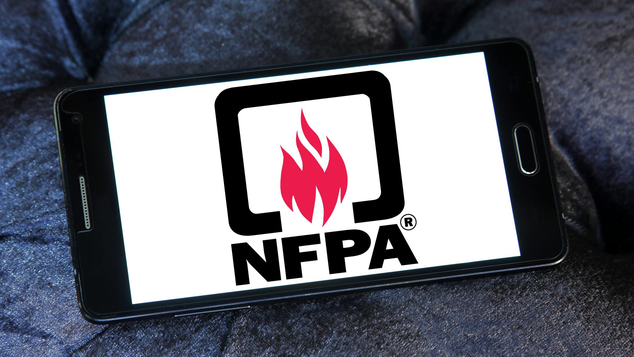 A smart phone is laying sideways on a dark background. The screen shows the NFPA logo against a plain white background.