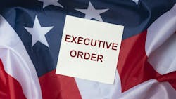 A white box that says 'EXECUTIVE ORDER' in red all caps lays across an american flag background A white box that says 'EXECUTIVE ORDER' in red all caps lays across an american flag background