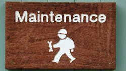 A wooden sign with white writing says 'Maintenance.' Below is a graphic of a construction worker wearing a hard hat and holding a wrench. A wooden sign with white writing says 'Maintenance.' Below is a graphic of a construction worker wearing a hard hat and holding a wrench.