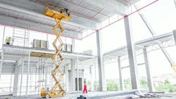A yellow scissor lift stands in a construction site. A yellow scissor lift stands in a construction site.