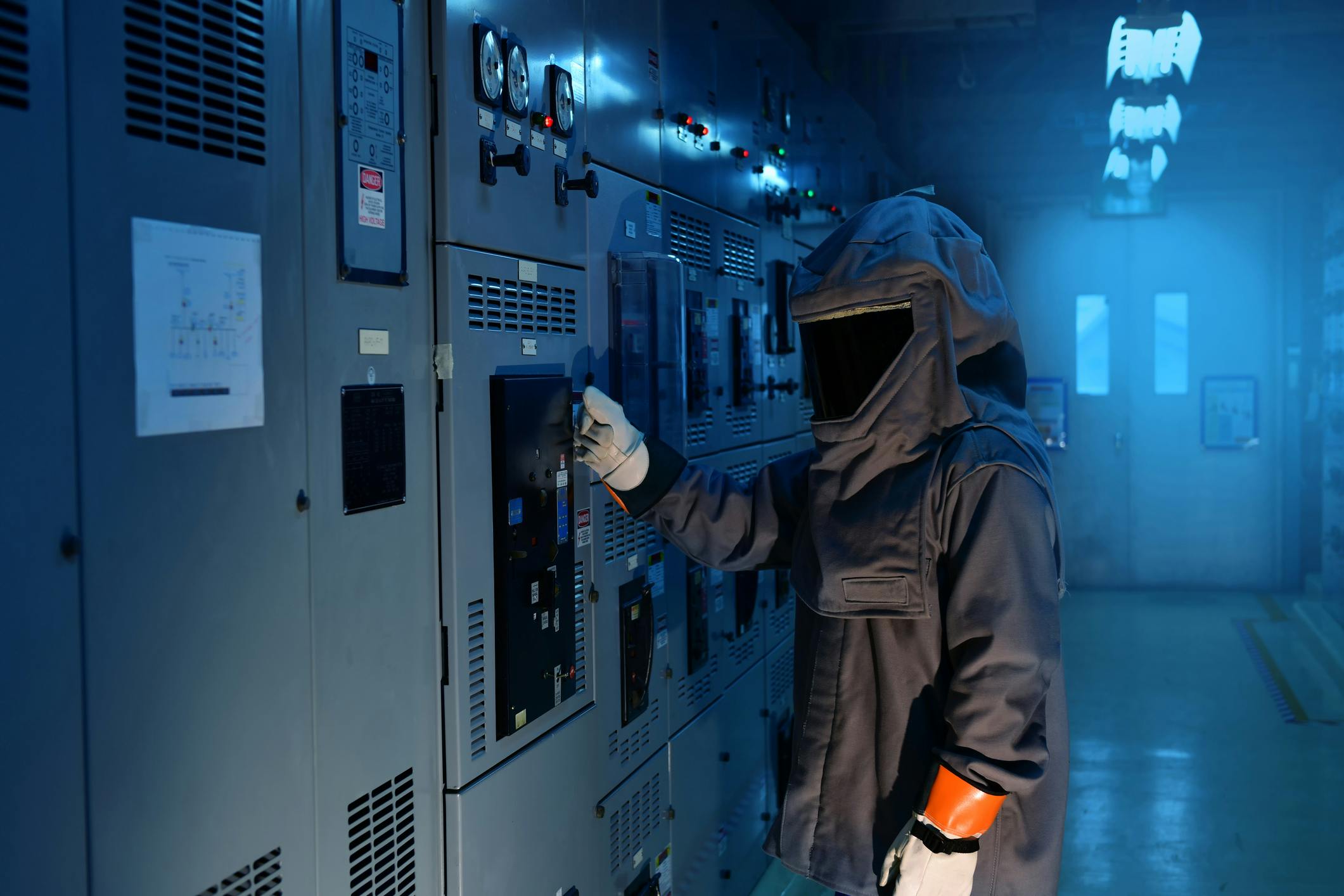 An electrical worker wearing an arc flash suit working on electrical equipment