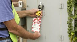 Man attaching a lockout tag to an electrical control panel Man attaching a lockout tag to an electrical control panel