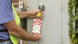 Man attaching a lockout tag to an electrical control panel Man attaching a lockout tag to an electrical control panel