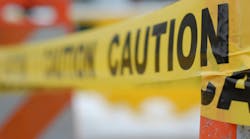 Photo of a yellow CAUTION tape draped over an orange cone in city traffic. Shallow depth of field. Photo of a yellow CAUTION tape draped over an orange cone in city traffic. Shallow depth of field.