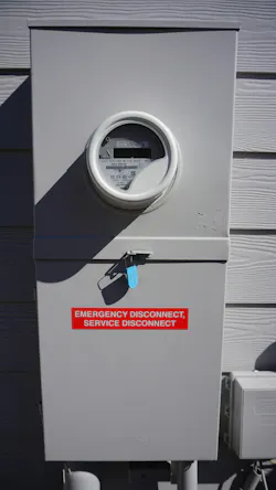 Photo 5. NEC Sec. 230.70 requires service disconnects to be located outdoors and readily accessible. For one- and two-family dwellings, the disconnect must be marked “EMERGENCY DISCONNECT” with minimum half-inch white letters on a red background. Other than one- and two-family dwellings must be marked “SERVICE DISCONNECT.” There is no prohibition against marking this one-family dwelling “SERVICE DISCONNECT” as long as the marking “EMERGENCY DISCONNECT” appears. Photo 5. NEC Sec. 230.70 requires service disconnects to be located outdoors and readily accessible. For one- and two-family dwellings, the disconnect must be marked “EMERGENCY DISCONNECT” with minimum half-inch white letters on a red background. Other than one- and two-family dwellings must be marked “SERVICE DISCONNECT.” There is no prohibition against marking this one-family dwelling “SERVICE DISCONNECT” as long as the marking “EMERGENCY DISCONNECT” appears.