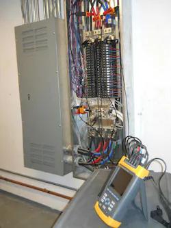 Photo 2. The use of sophisticated test equipment requires training on the test equipment, an understanding of the distribution system operation, and the use of safe work practices. This power quality analyzer with nine current, voltage, and ground leads connected inside this 3-phase panelboard identified the cause of an overheating problem due to harmonics. As a result, possible equipment failure and replacement was averted.