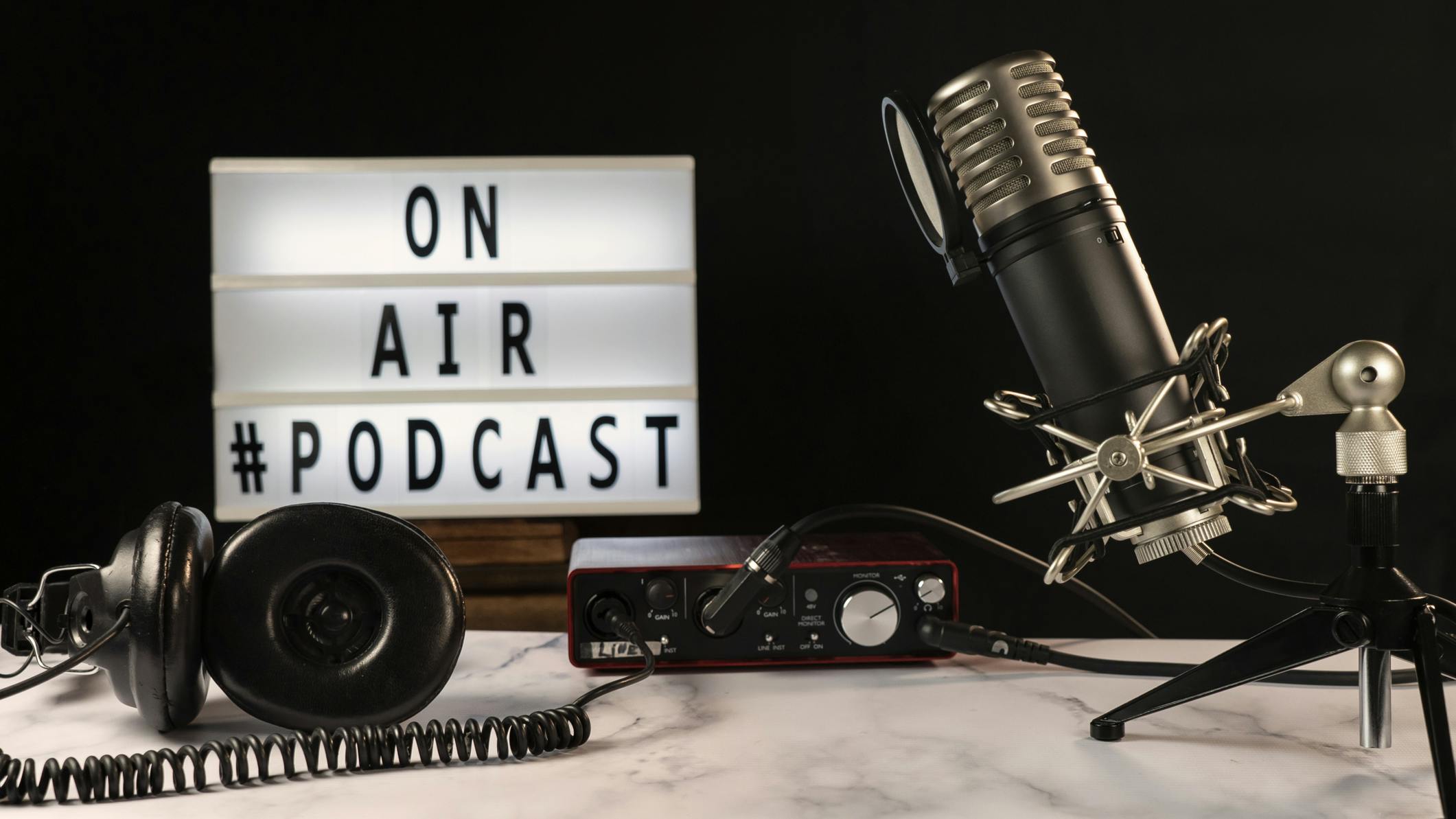 Podcast studio set with microphone, headphones, console and on air sign turned on,. Podcast studio set with microphone, headphones, console and &ldquo;on air&rdquo; sign turned on, over marble table and black background.