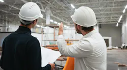 Architect and builder look on blueprint building under construction. Engineer and worker wearing safety hard hat have meeting on construction site