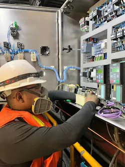 A technician performs maintenance on electrical equipment, a key part of assessing system condition and determining whether aging components can remain in service.