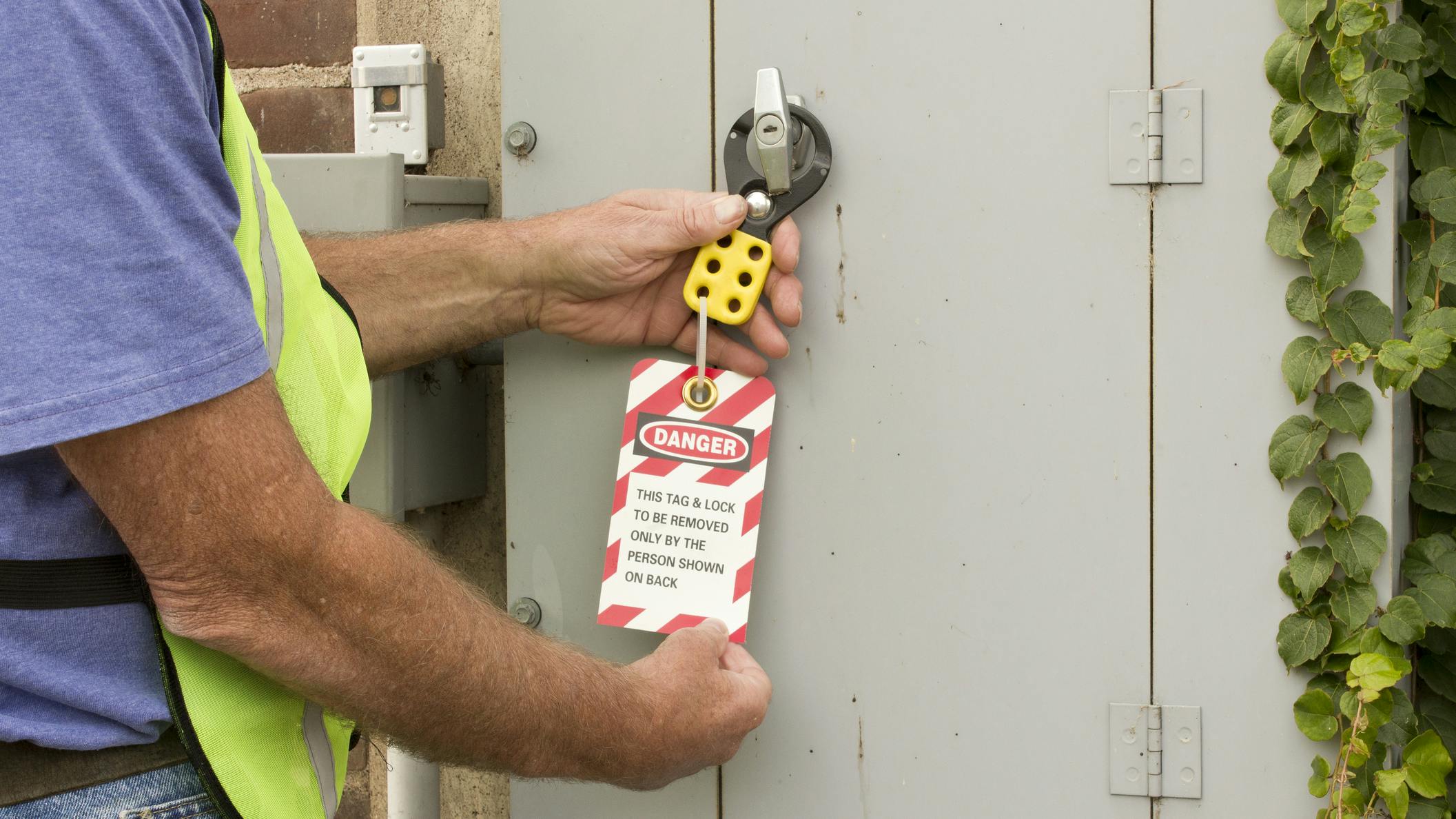Man attaching a lockout tag to an electrical control panel